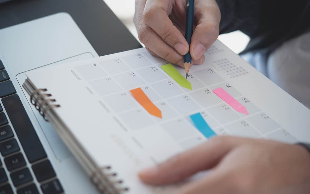 2024 Calendar event planning timetable agenda plan on organize schedule. Event planner agenda organizing by organizer schedule. Business man hand note on notebook with calendar planner on office table planning commercial painting project
