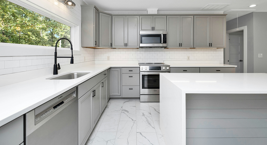 Modern kitchen featuring gray cabinets, stainless steel appliances, and white countertops, showcasing a stylish and functional design ideal for cabinet painting consultations.