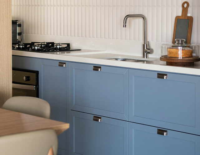 Modern kitchen with blue cabinets, white countertop, stainless steel faucet, and gas stove, showcasing stylish cabinet painting options for a kitchen transformation.